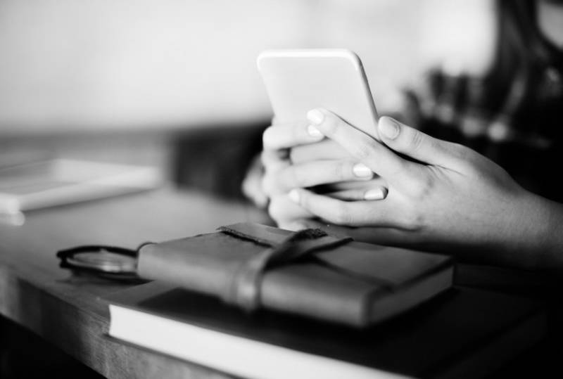 woman-using-cellphone-bible-on-table