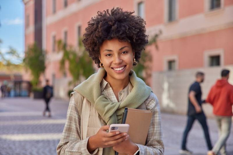 young-woman-student-holds-smartphone-outside-school-money-saving-app