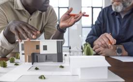 Two Men Property Models on Table Commercial vs. Residential Investment