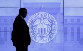 Security guard walks by an image of the Federal Reserve