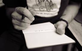 man-holding-pen-writing-on-notepad