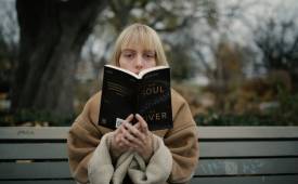 woman-sitted-on-bench-outside-reading-book