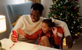 man-daughter-christmas-watching-tv-on-smartphone-memorable-christmas-tv-specials