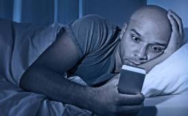man-reading-on-smartphone-in-bed-mass_text_messaging