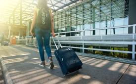 young-woman-backshot-travelling-pulling-suitecase-airport-terminal