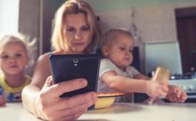 mother-with-todlers-checking-phone-tax-on-mothers-reduced-hours-lower-pay-unemployment