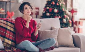 woman-smiling-couch-christmas-tree-using-ai-smartphone - illustration