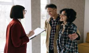 Real Estate Agent Woman Talking to the Couple While Holding a Clipboard