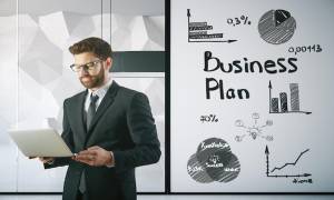 man-suite-standing-laptop-business-plan