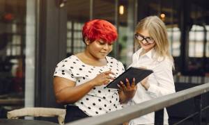 two-female-entrepreneurs-experience-tablet-smiling-colleagues