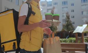 woman_food_courier_in_uniform_carrying_food_in_paper_bag_and_takeaway