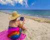 woman-holidaymaker-using-tablet-on-the-beach
