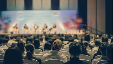 Rear view of audience listening speakers on the stage at a business event conference.j