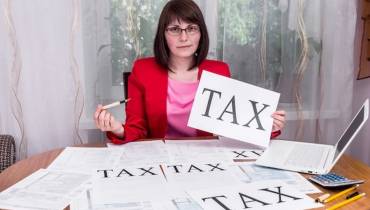 Woman_showing_word_tax_on_sheet_of_paper