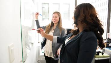 business-ladies-writing-on-whiteboard-corporate-simplification