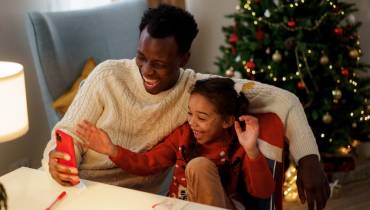 man-daughter-christmas-watching-tv-on-smartphone-memorable-christmas-tv-specials