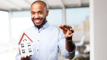 Man Happy Holding House Model and Keys to Property Image for Key Factors to Consider When Buying a Real Estate Property