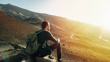 man-with-rucksack-sitting-rock-sunset-mountain-nature-for-creative-inspiration-inner-healing 