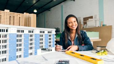 Smiling Businesswoman model of building Image for How to Start a Real Estate Business with No Money Out of Your Pocket