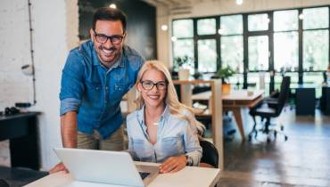 two-small-business-owners-male-female-using-laptop-smiling