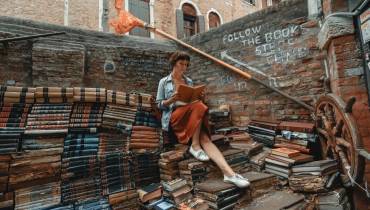 woman-reading-book-sitted-on-pile-of-books-literature-city