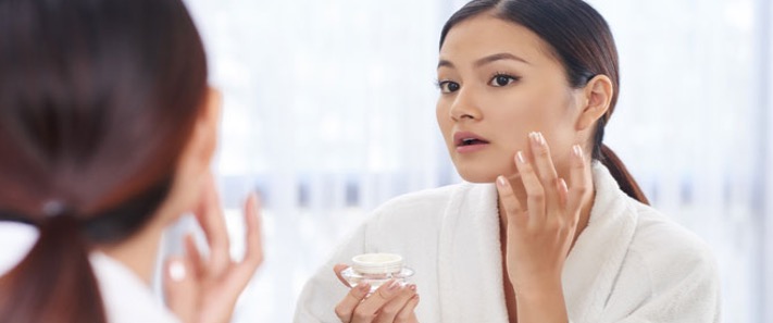 asian-woman-skin-tone-applying-skincare-product-mirror.jpg