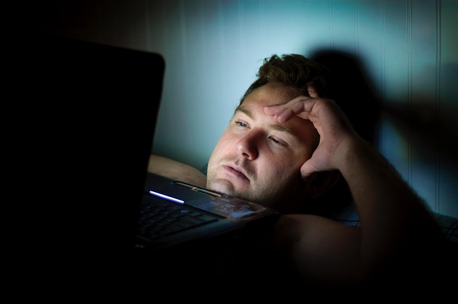 man-lying-down-looking-at-laptop-screen-addiction-research.jpg