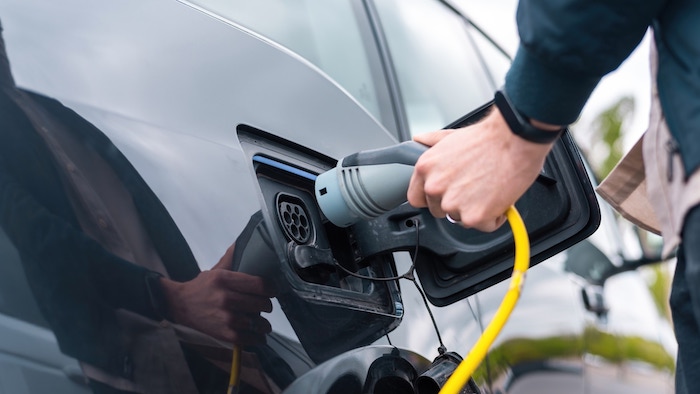 man-plugging-charger-into-electric-car-charge-station.jpg