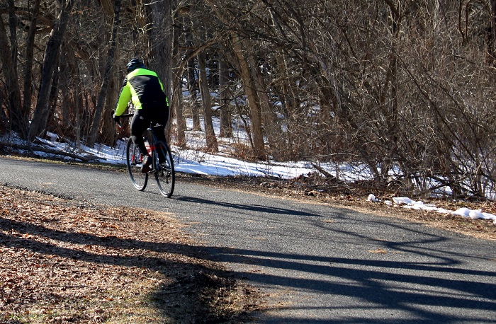 speeding_bicyclist_his_legs_pumping_furiously_as_he_rounds_a_paved_trail_curve.jpg