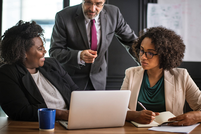 two-female-b2b-employees-and-boss-with-laptop-on-table-smiling.png