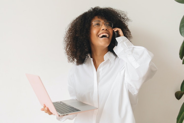 woman-happy-working-laptop-talking-on-smartphone