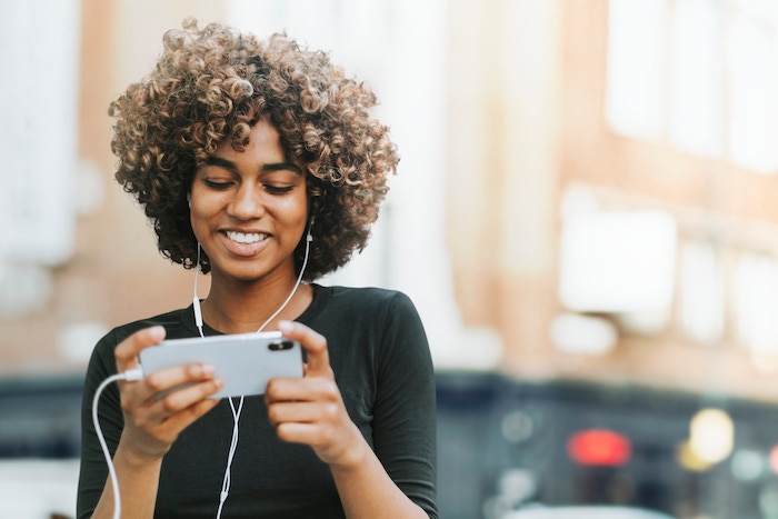 woman-wearing-earphones-city-streaming-media-on-smartphone