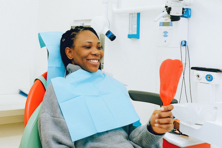 woman_holding_orange_mirror_recovering_from_dental_gum_procedure