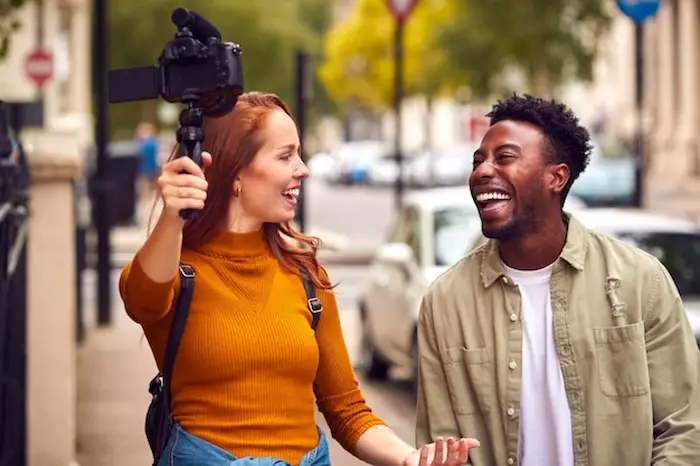 young-woman-and-young-man-vlogging-to-video-camera-on-handheld-tripod