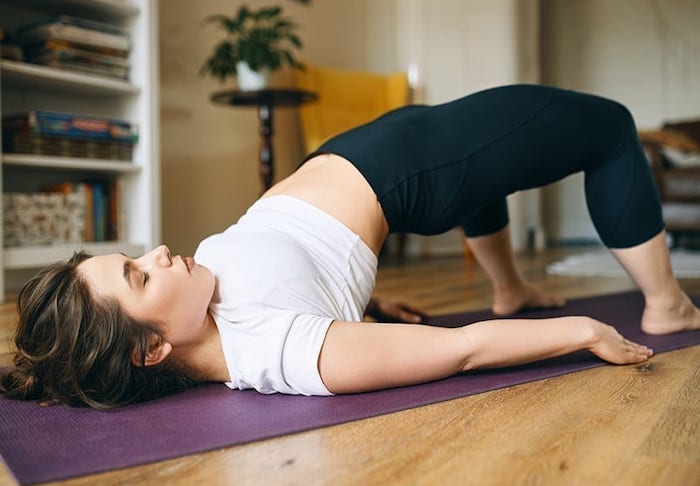 young-woman-doing-kegel-exercises-lying-mat-with-feet-floor-bending-knees