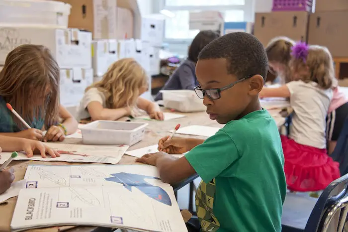 young_african-american_schoolboy_focused_on_a_drawing_book_in_class 
